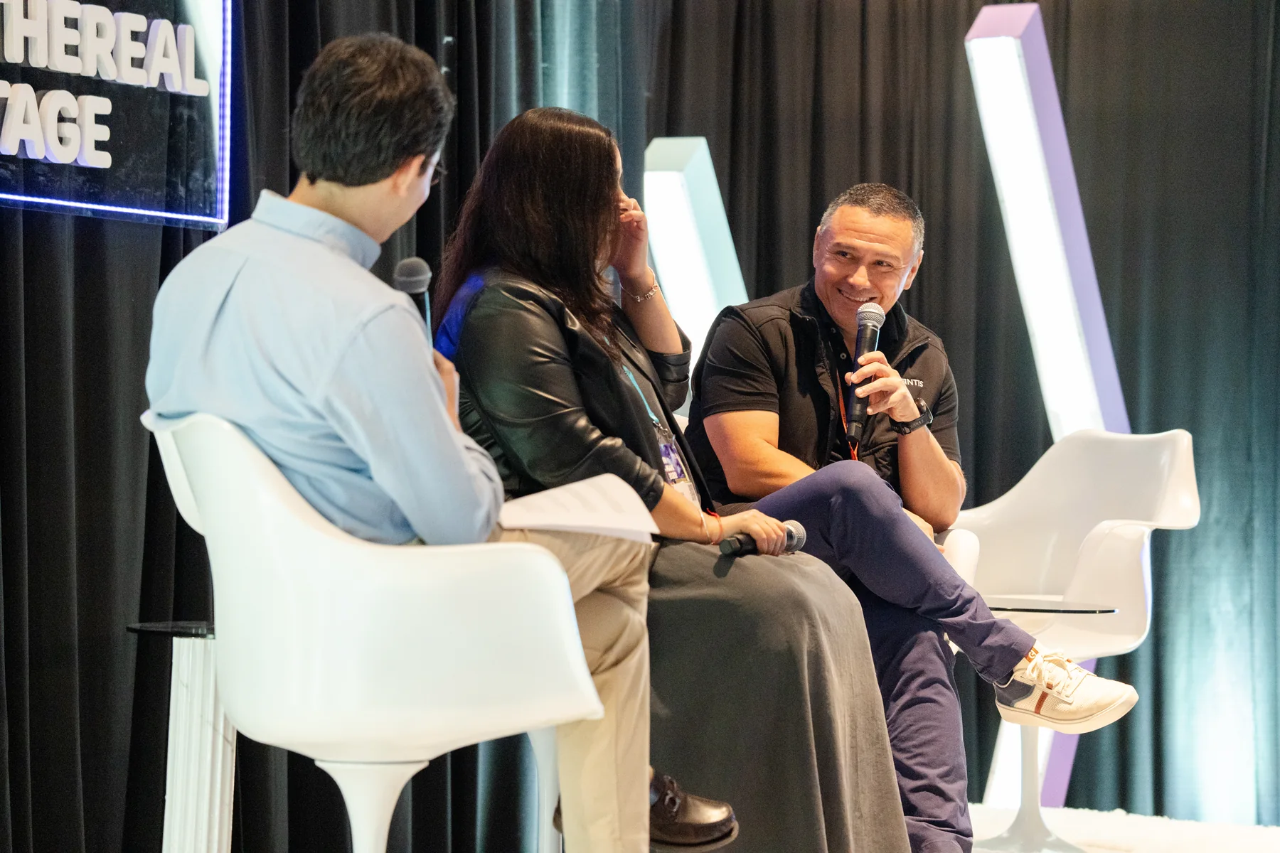 Three-person panel discussion on a branded conference stage
