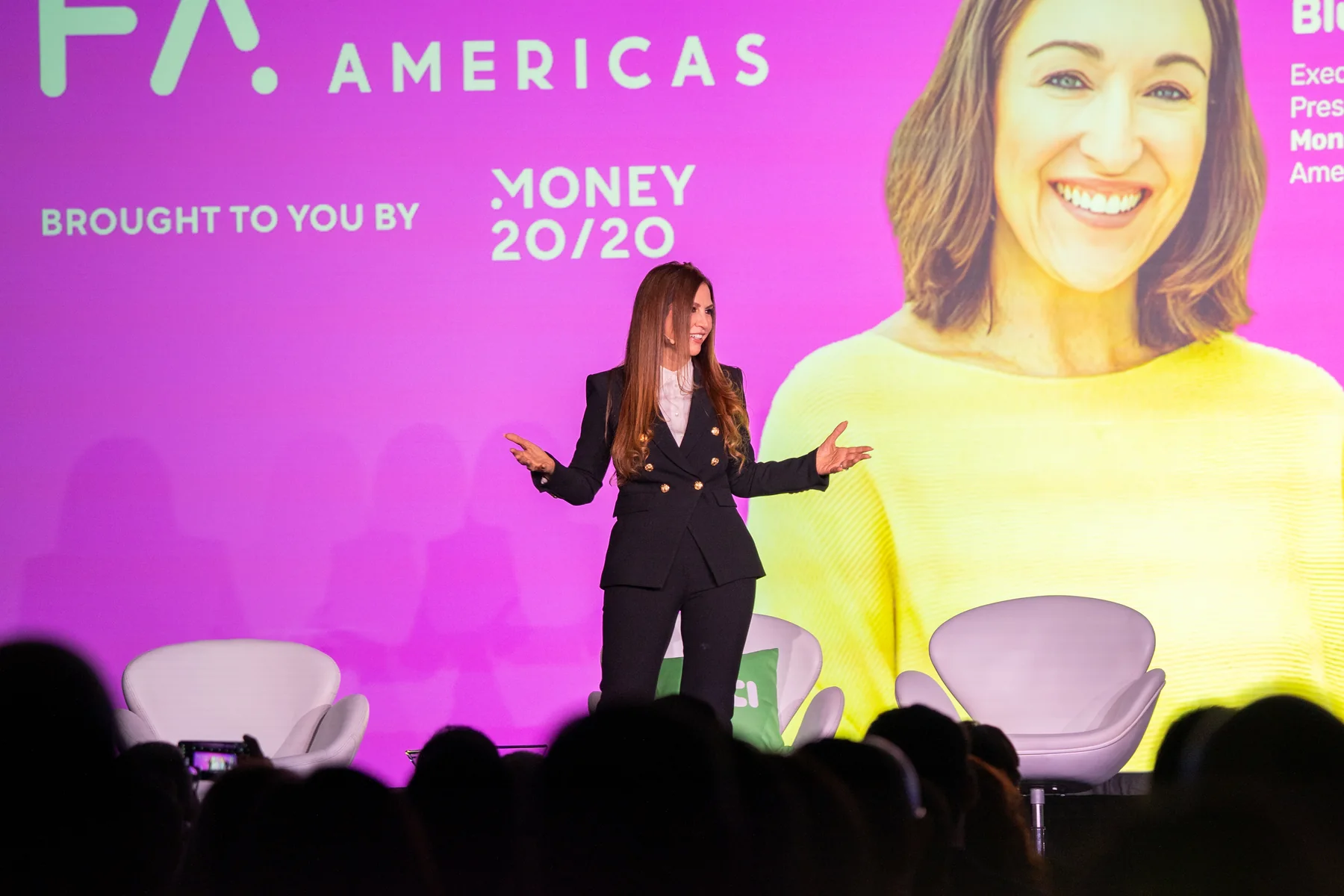 Keynote speaker on stage with colorful conference screen