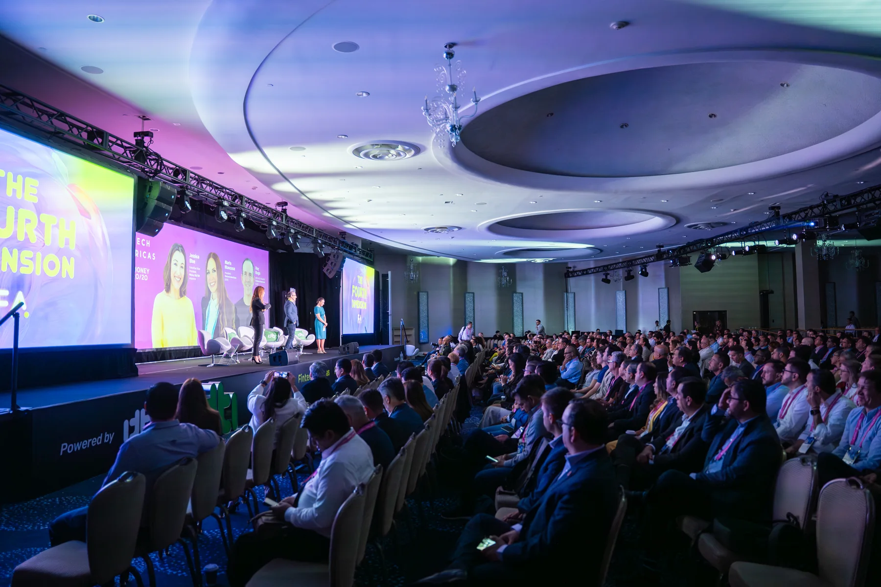 Wide conference room with keynote stage and seated corporate audience